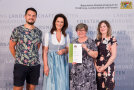 4 Personen stehen nebeneinander, eine davon hält Urkunde
