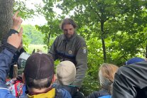 Ein Mann, der Forstpate, steht mit Kindern bei Waldjugenspielen