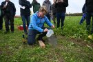 Junger Mann gießt auf dem Feld Wasser in einen Metallring.