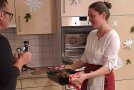 Frau präsentiert Braten in Rein. Mann filmt.