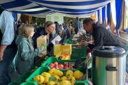 Obststandbetreiber unterhält sich mit Frau und ihrer Tochter