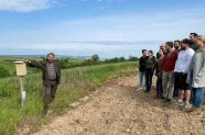 Forststudenten stehen auf einem Feld und hören Schönberger zu.