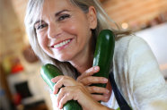 Seniorin hält in jeder Hand eine Zucchini 