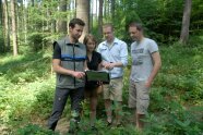 Personen im Wald blicken auf Laptop von Förster